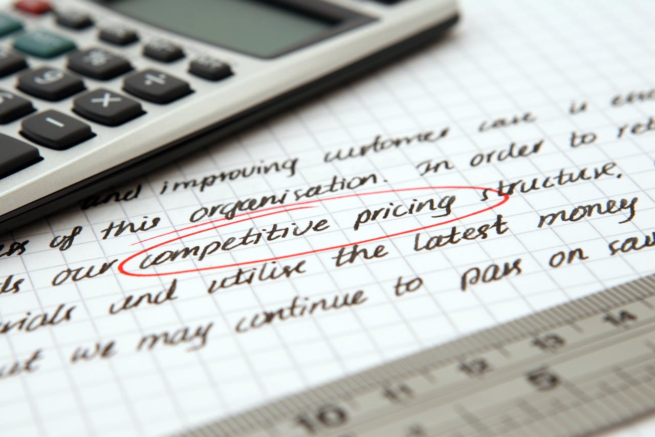 Dla Firm Focused image of handwritten business notes with calculator emphasizing pricing strategy.