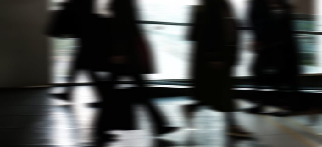 Abstract blurred motion of people walking indoors, depicting urban life and busy routines.